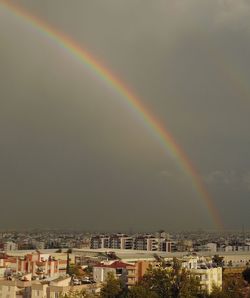 Rainbow over buildings in city against sky