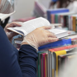 Midsection of woman reading book at bookstore