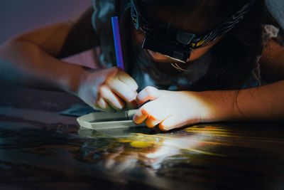 Cropped hands of woman holding jigsaw pieces on table