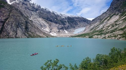 People canoeing in lake against mountains during winter