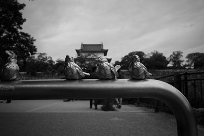 Birds perching on statue against sky