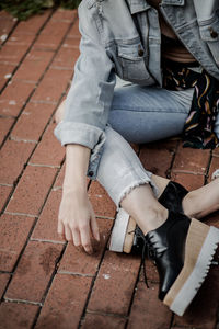 Low section of woman sitting on sidewalk