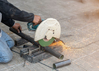 Worker use circular fiber cuttinng machine with spark cut metal pipe in workshop..