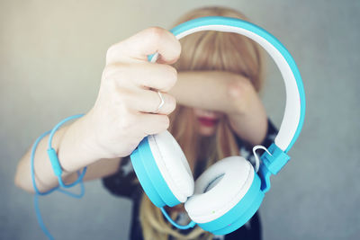 Woman holding headphones while standing against wall