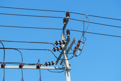 Low angle view of electricity transformer against clear blue sky