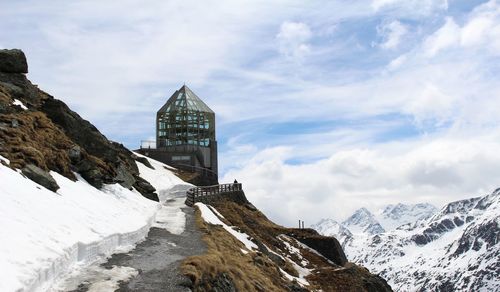 Building on snowcapped mountain against sky