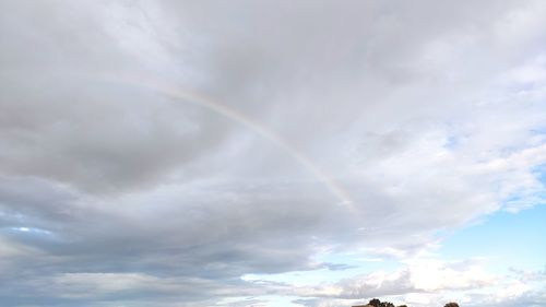 Low angle view of rainbow against cloudy sky