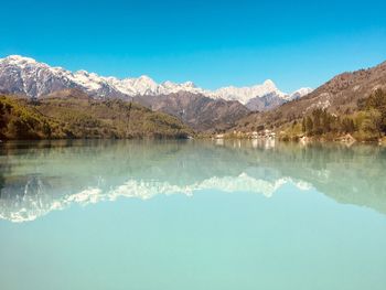 Scenic view of lake and mountains against clear blue sky