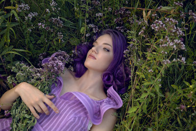 Teenage girl with dyed purple hair and a nose piercing in the grass  in a short dress