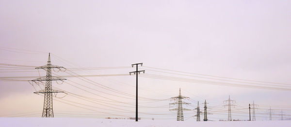 Low angle view of electricity pylons against clear sky