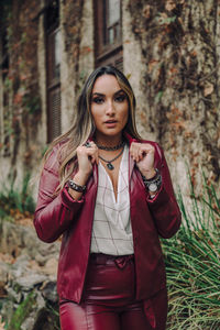 Portrait of beautiful young woman standing against tree