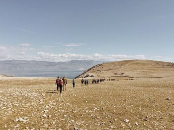 Rear view of people hiking in desert against sky