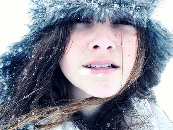 Close-up portrait of teenage girl wearing fur hat during snowfall