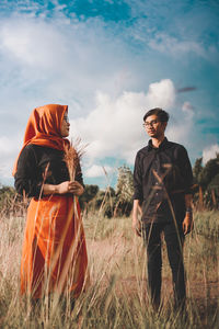 Couple standing on field against sky