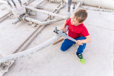 High angle view of cute boy repairing water pipe