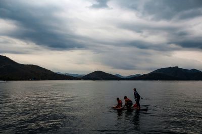 People enjoying in lake against sky