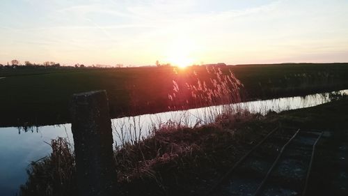 Scenic view of farm against sky during sunset