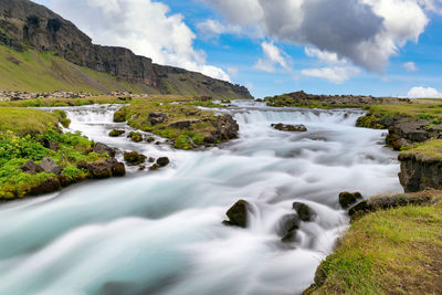 Scenic view of waterfall by sea against sky