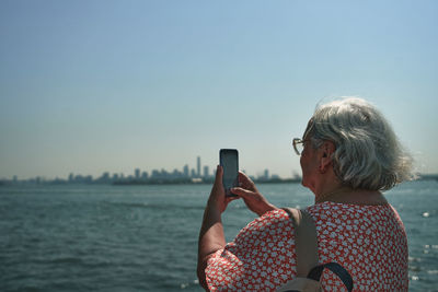 Young woman using mobile phone against sky during sunset