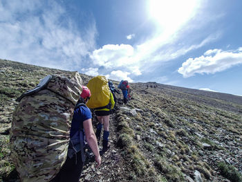 Rear view of man climbing on mountain against sky