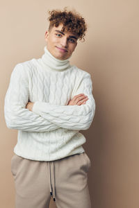 Portrait of young woman standing against pink background