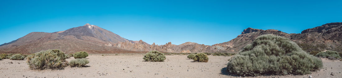 Panoramic view of rocky mountains against clear blue sky