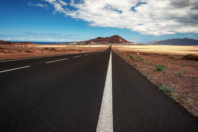 Road leading towards mountain range against sky