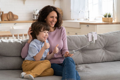 Smiling mother and son using smart phone at home