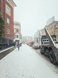 Cars on street by buildings against sky in city