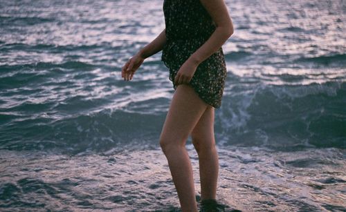 Midsection of woman standing on shore at beach