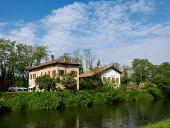 Houses by lake against sky