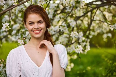 Portrait of young woman standing against plants