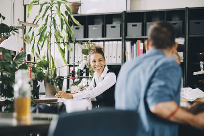 Smiling businesswoman looking at male colleague while working in creative office