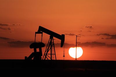 Orange sunset and pump jack silhouette in the texas oilfield