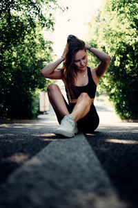 Young woman with arms raised on road in city