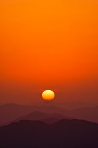 Scenic view of silhouette mountains against the orange sky