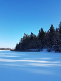 Scenic view of lake against clear blue sky during winter