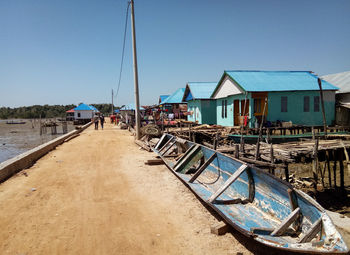 Boats moored on beach by buildings against clear sky