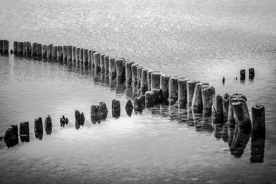 Wooden posts in sea against sky