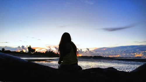 Woman on beach against sky during sunset