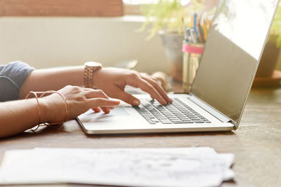 Midsection of woman using laptop on table