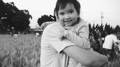 Portrait of smiling girl standing on field against sky