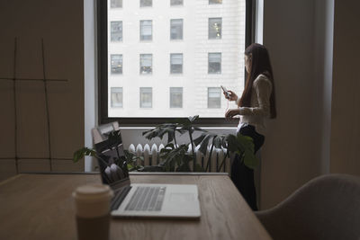 Young woman in workplace with her smart phone.