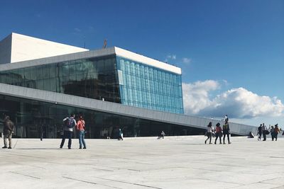 People walking on modern building against sky in city