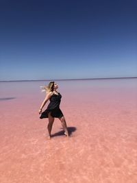 Woman standing in sea against clear sky