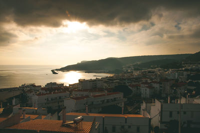 High angle view of townscape by sea against sky at sunset