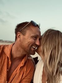 Side view of couple kissing against sky