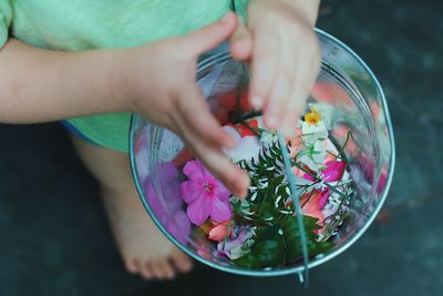 Low section of kid holding flower in bowl