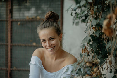 Portrait of smiling young woman sitting by plants