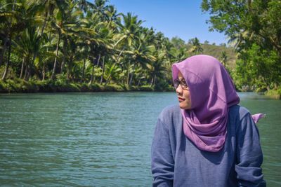 Woman in hijab by lake on sunny day
